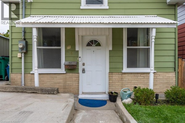 Close-up of the front door with white siding, brick base, and windows. - 71 Beverly Street, Cambridge