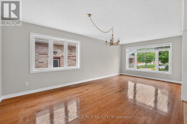 Living room with hardwood floors, gray walls, and large windows overlooking the street. - 71 Elmwood Avenue, Brock