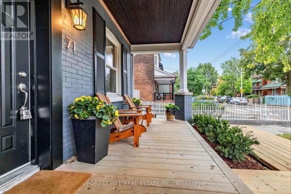 Another view of the front porch, showing seating and green bushes. - 71 Emerson Avenue, Toronto