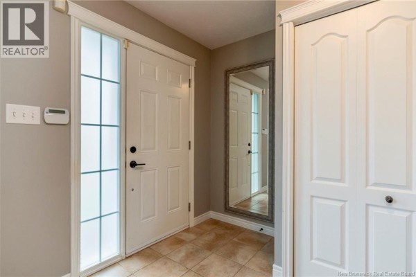 Interior entryway with a white front door, frosted glass sidelight, tiled floor, and a large mirror. - 71 Houlahan Street, Dieppe