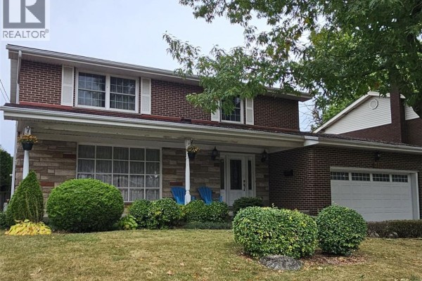 View of the house from the right, highlighting the garage door, brickwork, and surrounding green shrubs. - 71 Margate Avenue, Hamilton