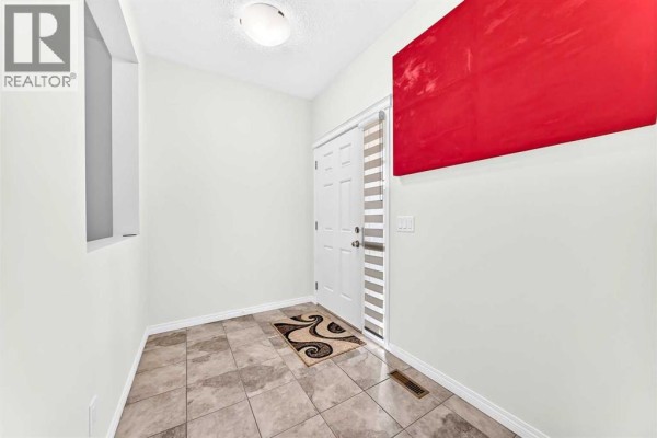 Interior entryway with tiled floor, white door, and a large red art piece. - 71 Martha's Meadow Close Ne, Calgary