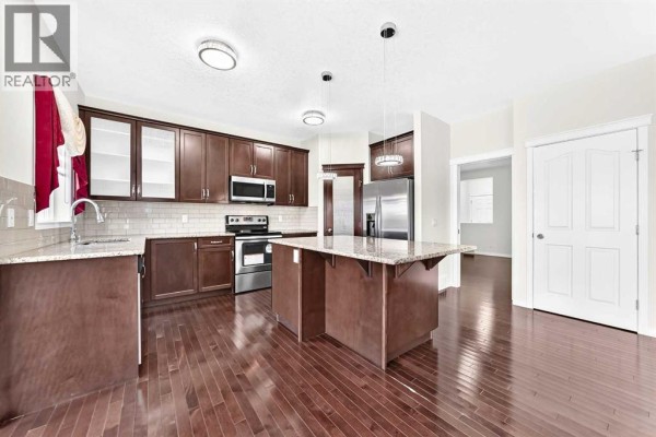 Kitchen with dark brown cabinets, granite countertops, stainless steel appliances, and an island. - 71 Martha's Meadow Close Ne, Calgary