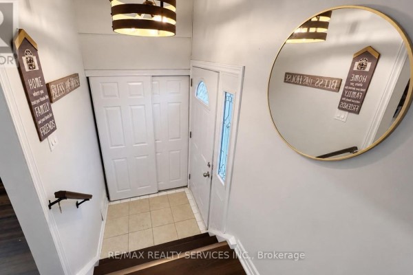 Tiled entryway with white bi-fold doors and a large round mirror. - 71 Newlyn Crescent, Brampton