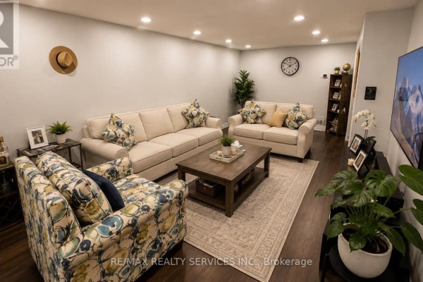 Living room with two beige sofas, floral armchair, and dark wood coffee table. - 71 Newlyn Crescent, Brampton