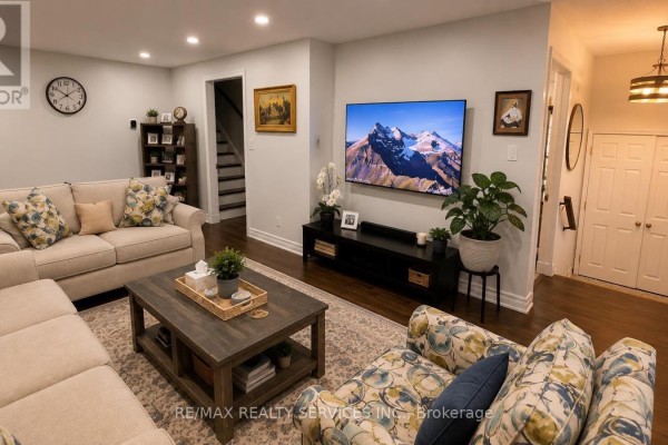 Living room with beige sectional, floral accent chair, and mounted television. - 71 Newlyn Crescent, Brampton