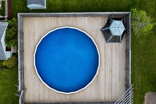 Overhead view of a round above-ground swimming pool surrounded by a wooden deck. - 71 Rebecca Drive, Summerside