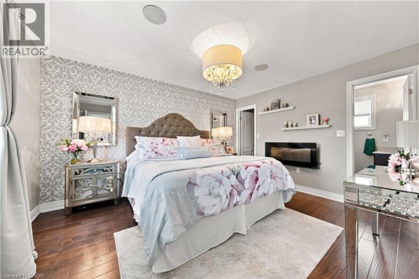 Bedroom with floral bedding, electric fireplace, and mirrored nightstand - 71 Riviera Ridge Stoney Creek
