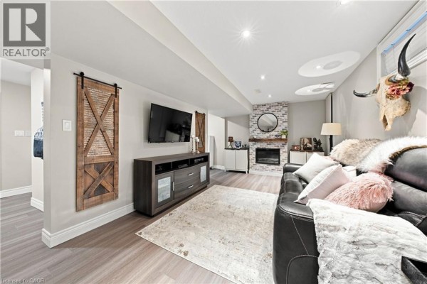 Living room with fireplace, TV, and leather sofa - 71 Riviera Ridge Stoney Creek