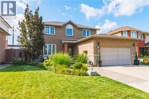Wide shot of the property exterior showcasing the brick facade, garage, and landscaping. - 71 Riviera Ridge, Stoney Creek