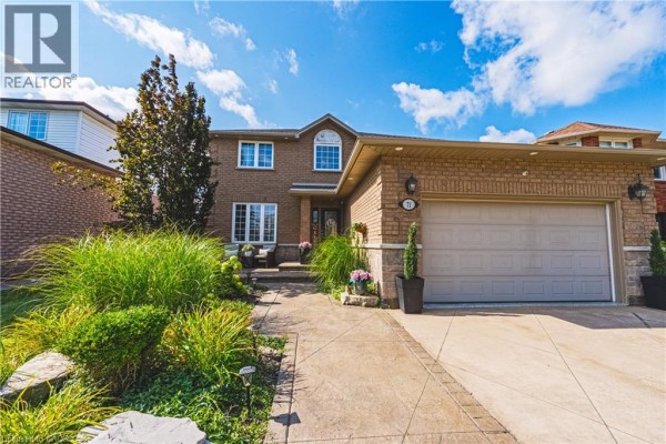 Daylight exterior view of a large brick house with a prominent front entrance and garage. - 71 Riviera Ridge, Stoney Creek