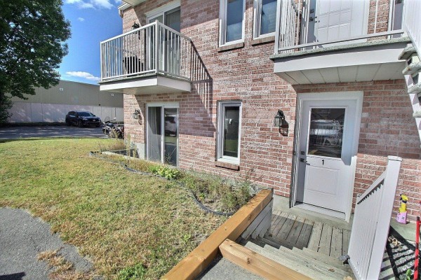 Side entrance to apartment 1 with a small green lawn and stairs leading down. - 71 Rue De Sauternes, #1, Gatineau