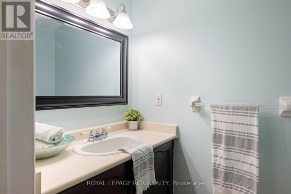 Close-up of a powder room vanity with a white sink, black cabinet, and light blue walls. - 71 Shirley Street, Orangeville
