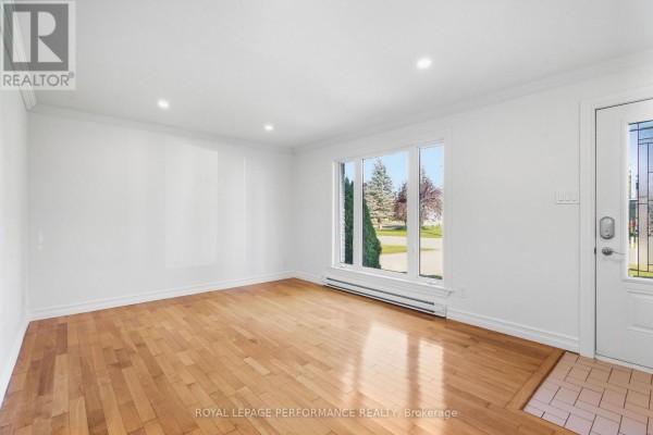 Living room with hardwood floors, white walls, and a large front-facing window. - 71 Stephens Street, Champlain