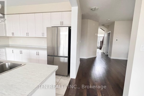 Open concept kitchen and dining area with white cabinets and a wooden table. - 71 Sundin Drive, Haldimand