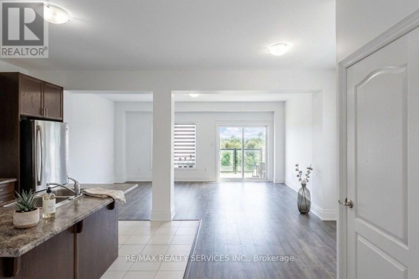 Open-concept living area with dark wood floors, white walls, and a balcony view. - 71 Sunset Way, Thorold
