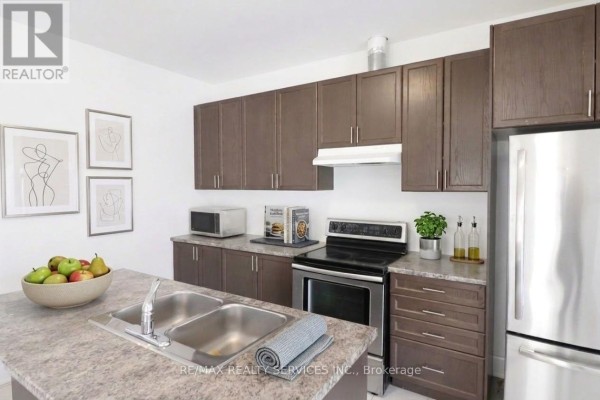 Kitchen with dark brown cabinets, stainless steel appliances, and a center island sink. - 71 Sunset Way, Thorold
