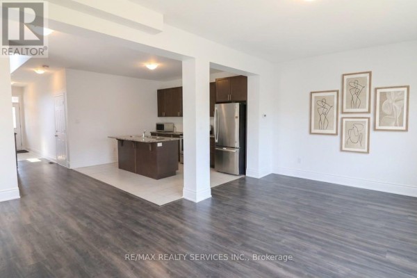Living space with dark wood floors and a view into the open-concept kitchen area. - 71 Sunset Way, Thorold