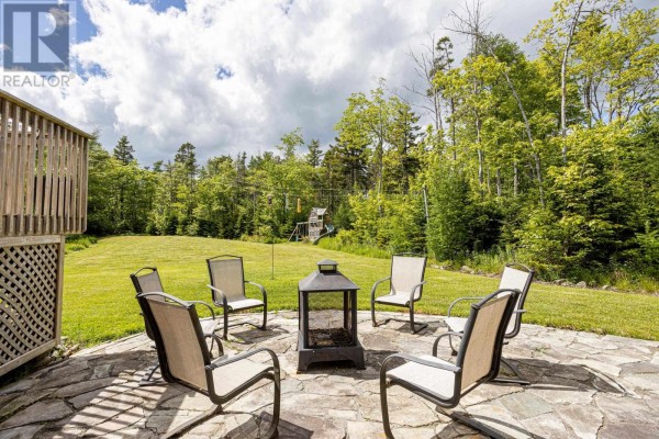 Stone patio with chairs and a fire pit surrounded by trees. - 71 Yezen Court, Hammonds Plains