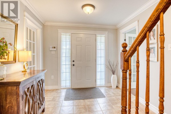 Foyer with a white front door, tiled floor, and wooden staircase. - 71 Yezen Court, Hammonds Plains
