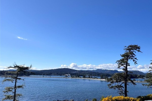 Vast blue sky over calm blue water with distant green, tree-covered hills and a spit of land. - 7100 Friendship Lane, Sooke