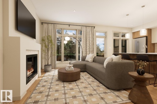 Living room with a gray sectional sofa, fireplace, large windows, and a glimpse of the kitchen island. - 7107 50a Av, Beaumont