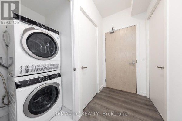 Laundry area featuring stacked washer and dryer in a hallway - 7108 - 138 Downes Street, Toronto