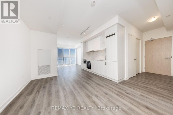 Open living area with large windows, light wood flooring, and modern kitchen layout - 7108 - 138 Downes Street, Toronto