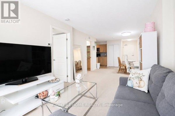 Living room showing sofa, TV, desk area, and doorway to kitchen. - 711 - 138 Somerset Street W, Ottawa