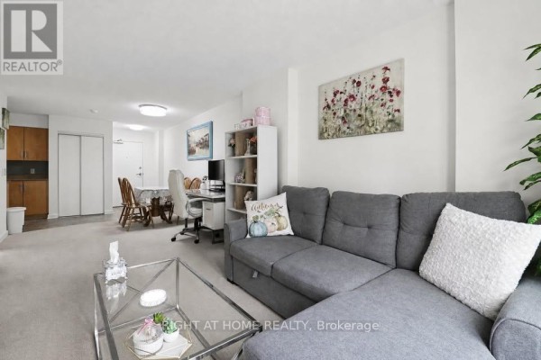 Living room with sectional sofa, dining table, desk, and kitchen view. - 711 - 138 Somerset Street W, Ottawa