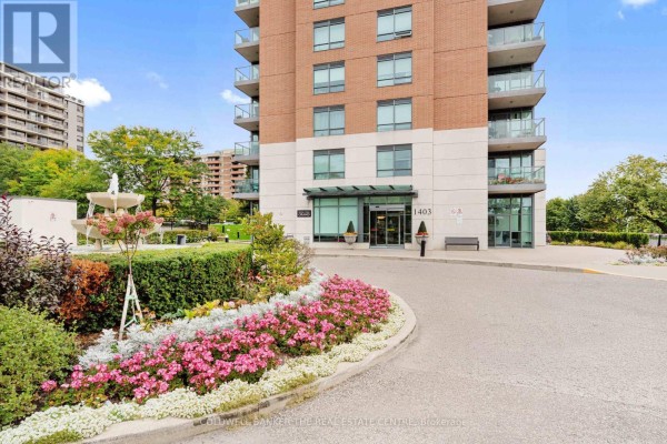 Entrance to apartment building 1403 Royal York Road with a manicured garden and pink flowers. - 711 - 1403 Royal York Road, Toronto