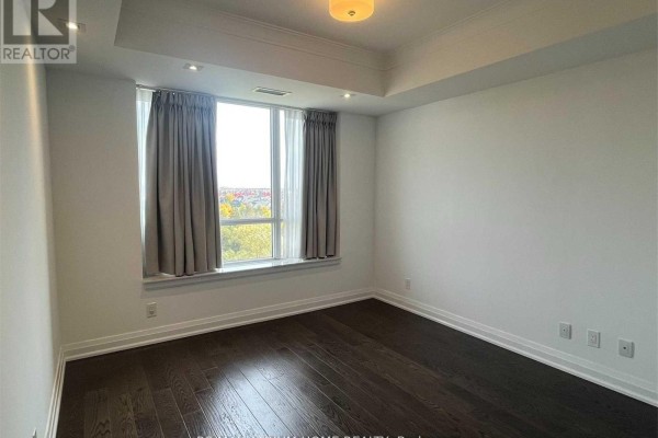 Empty bedroom with dark hardwood floors and a large window with beige curtains. - 711 - 15 Stollery Pond Crescent, Markham