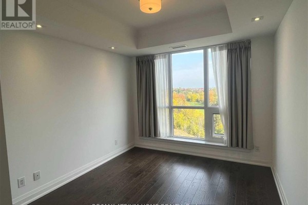 Empty bedroom with dark hardwood floors and a large corner window with beige curtains. - 711 - 15 Stollery Pond Crescent, Markham