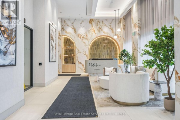Elegant building lobby with marble walls, modern seating, and a reception desk. - 711 - 2088 James Street, Burlington
