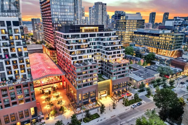 Aerial view of a modern condo building with surrounding cityscape at dusk. - 711 - 455 Wellington Street W, Toronto