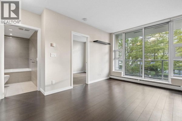 Living room with dark hardwood floors, beige walls, a large window, and an open doorway to a bathroom. - 711 1708 Columbia Street, Vancouver