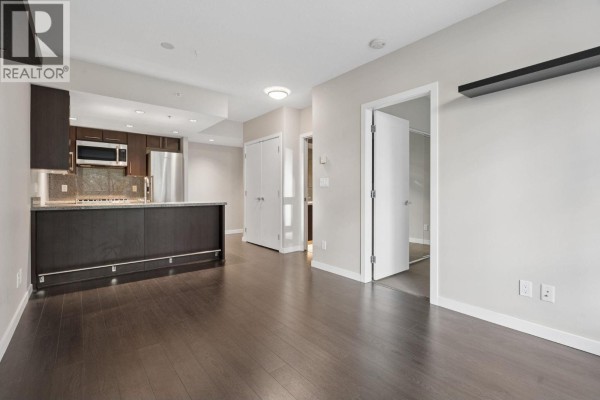 Living area with dark hardwood floors, a kitchen with dark cabinets, and doorways to other rooms. - 711 1708 Columbia Street, Vancouver