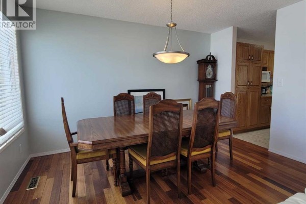 Dining room with wooden table, chairs, and access to kitchen area - 7110 99a Street, Peace River