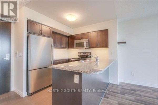 Kitchen with dark wood cabinets, granite countertops, and stainless steel appliances. - 712 - 25 Lower Simcoe Street, Toronto