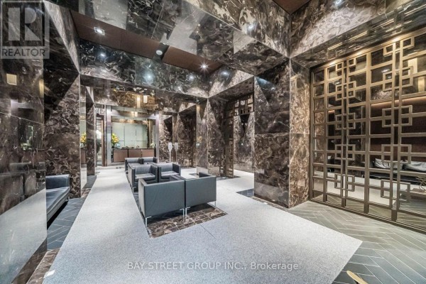 Luxurious lobby with dark marble walls, seating area, and decorative metal screen. - 712 - 70 Temperance Street, Toronto