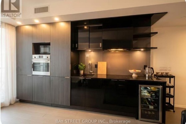 Sleek modern kitchen with dark cabinetry, integrated appliances, and wine fridge. - 712 - 70 Temperance Street, Toronto