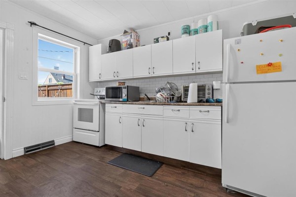 Kitchen with white cabinets, white appliances, subway tile backsplash, and dark wood-look floor. - 712 Martin Avenue E, Winnipeg