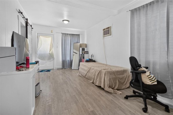 Living space with a bed, dresser, desk, chair, television, and light wood-look floor. - 712 Martin Avenue E, Winnipeg