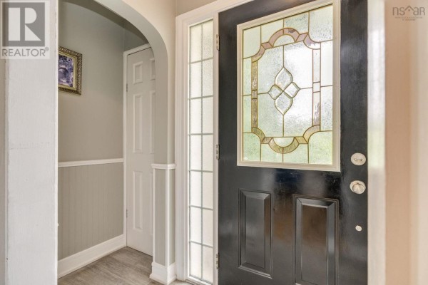 Entranceway with a dark wood door featuring a stained glass window and an arched doorway. - 712 Old Sambro Road, Halifax
