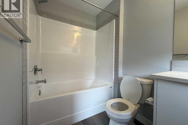 Bathroom with a white tub and toilet, and a grey vanity with a white countertop. - 712 Sage Hill Grove Nw, Calgary