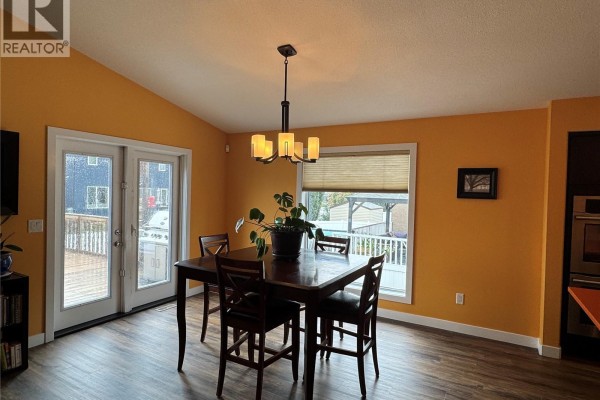 Dining area with a dark wood table and chairs, next to French doors leading to a deck. - 7122 Maple Vista Drive, Regina