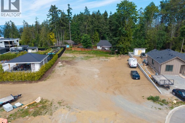 View of a cleared lot with new home construction to the left and right, featuring construction equipment. - 7128 Ocean Blue Pl, Lantzville