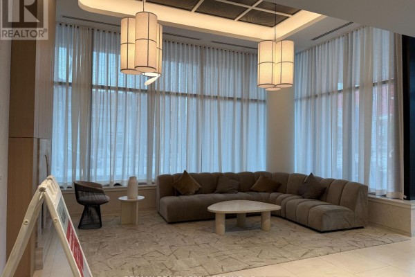 Close-up of lobby seating area with plush sectional sofa, decorative pillows, and modern pendant lights. - 713 - 30 Dreamer Way, Toronto