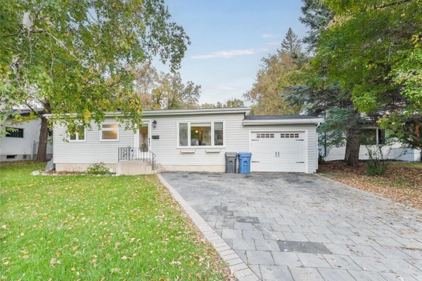 Front view of a one-story house with a green lawn, mature trees, and an attached single-car garage. - 713 Buckingham Road, Winnipeg