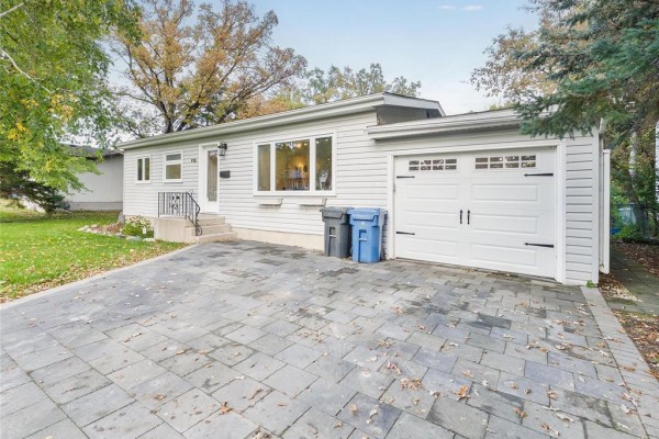 Street view of a single-family home with light grey siding, a modern garage door, and a paved driveway. - 713 Buckingham Road, Winnipeg